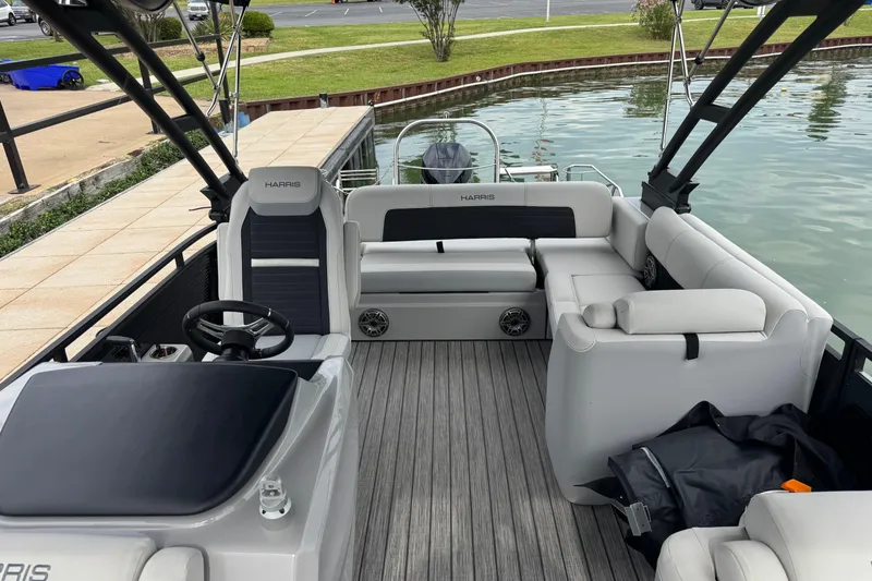 Slide: The Image of 2023 Harris Solstice 230 pontoon boat interior with seating and steering wheel by the dock. - 14