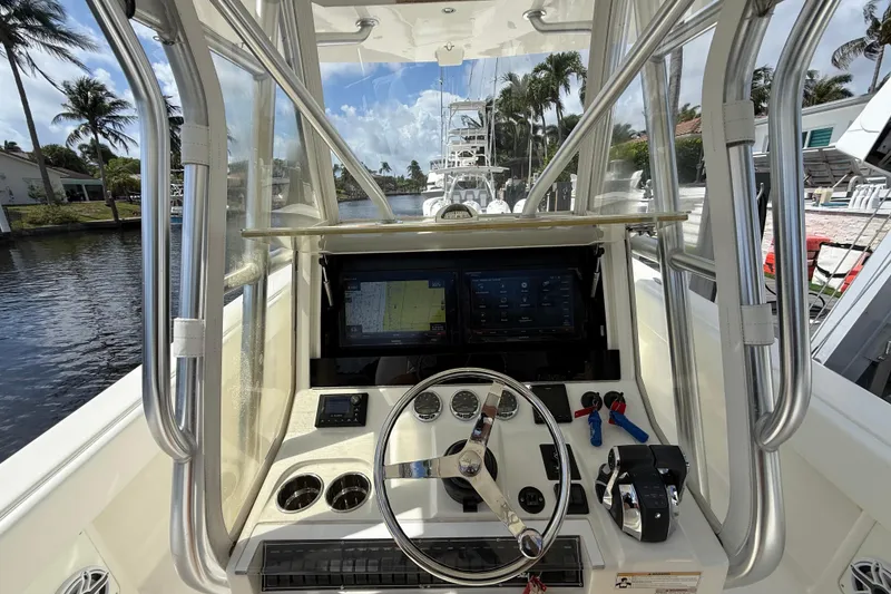 Slide: The Image of 2018 SeaVee 340Z boat helm with navigation screens and steering wheel, docked near palm trees. - 13
