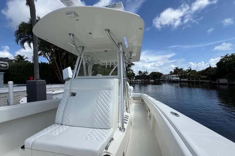 Slide: The Image of 2018 SeaVee 340Z boat with white seating, docked by a scenic waterfront. - 7