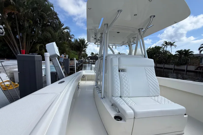 Slide: The Image of 2018 SeaVee 340Z boat with sleek white seating and modern design, docked by lush greenery. - 8