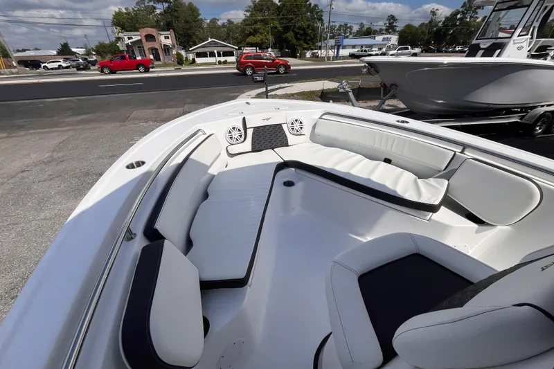 Slide: The Image of 2026 Tidewater 210 LXF boat interior with white seating and speakers, parked outdoors. - 10