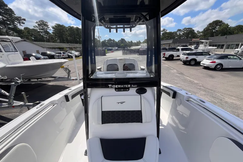 Slide: The Image of 2026 Tidewater 210 LXF boat interior with console and seating, parked outdoors. - 11