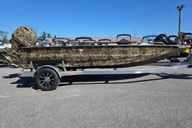 The Image of 2026 Excel 183 Tomahawk boat on trailer, camouflage design, parked outdoors. - 0
