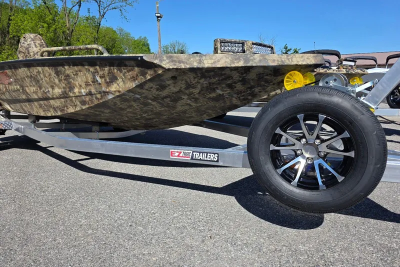 Slide: The Image of Camouflage Excel 183 Tomahawk boat on trailer, 2026 model, parked outdoors. - 1