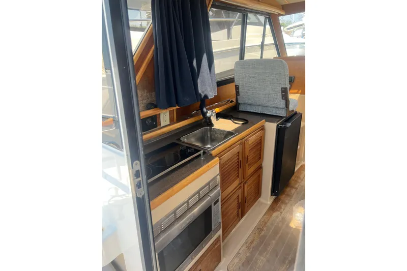 Slide: The Image of Interior of 2012 Cutwater 26 boat featuring kitchenette with sink, stove, and storage cabinets. - 4