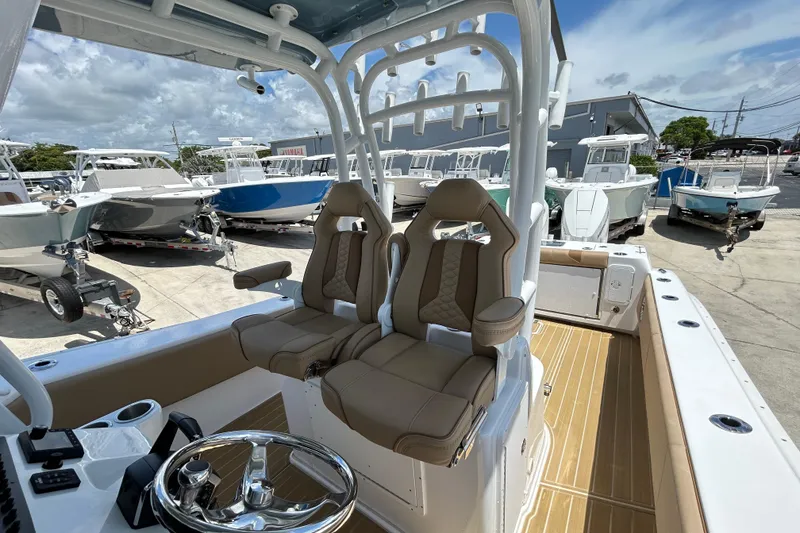 Slide: The Image of 2025 Cape Horn 34 XS boat interior with dual seats and steering wheel, docked among other boats. - 13