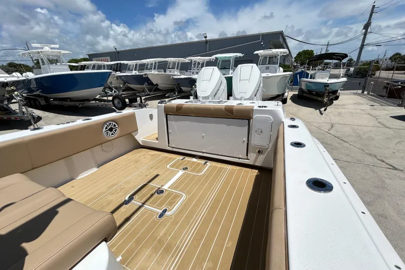 Slide: The Image of 2025 Cape Horn 34 XS boat interior with tan seating and wood flooring, docked outdoors. - 18
