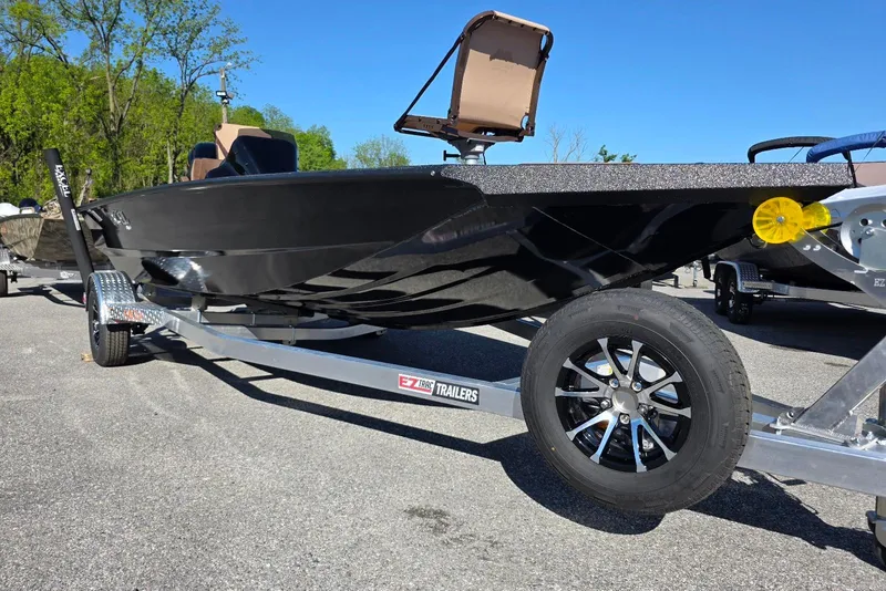 Slide: The Image of 2026 Excel EX 183 boat on trailer, black hull, parked outdoors. - 2