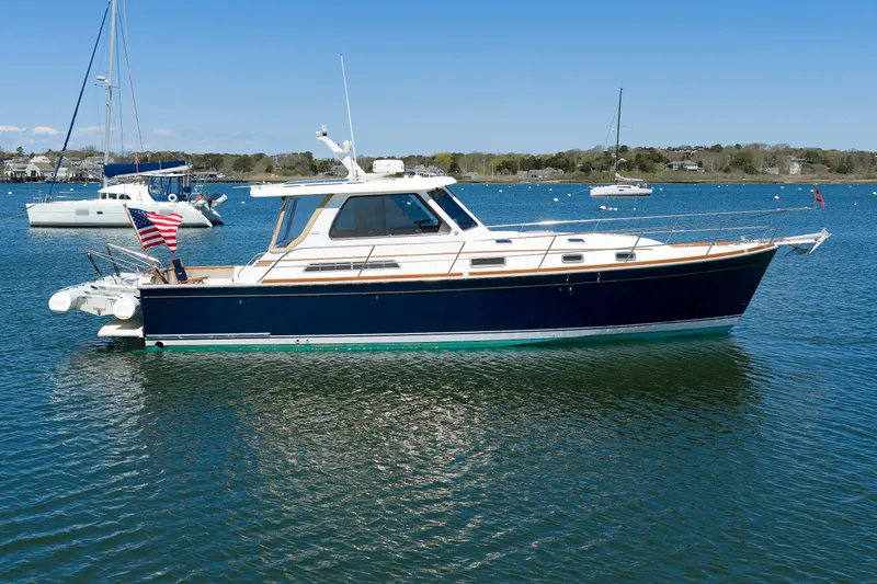 The Image of 2004 Sabre 42 Express yacht on calm water, with American flag, under clear blue sky. - 1