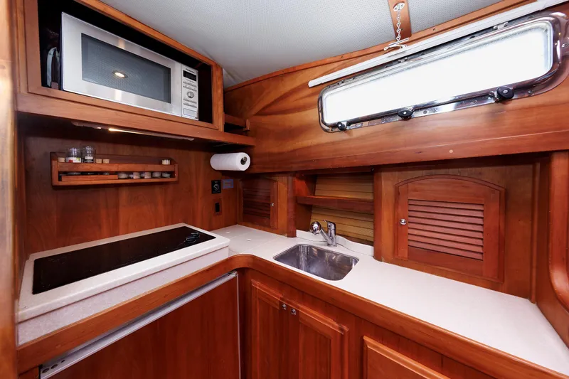 Slide: The Image of 2004 Sabre 42 Express yacht kitchen with microwave, stove, and wooden cabinetry. - 10