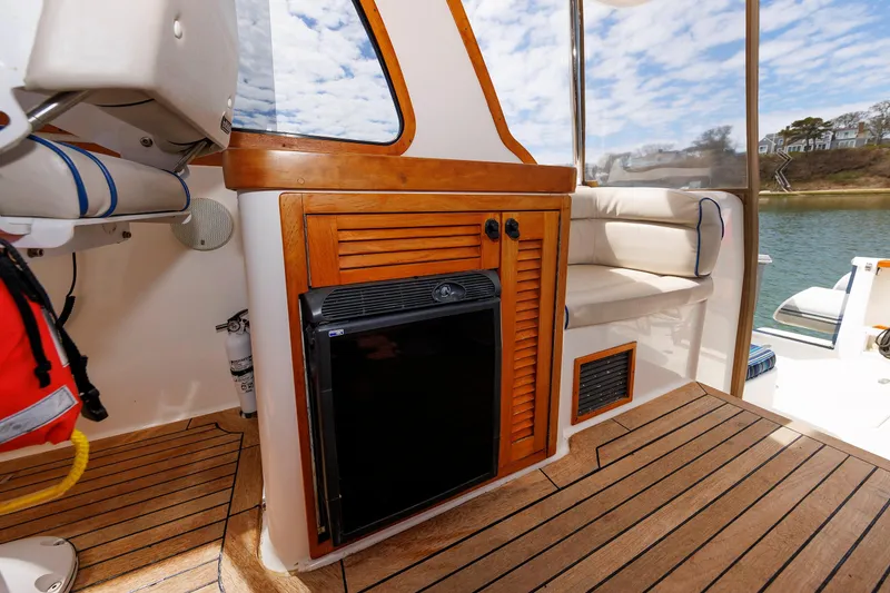 Slide: The Image of 2004 Sabre 42 Express yacht interior with wooden cabinetry and seating by the water. - 17