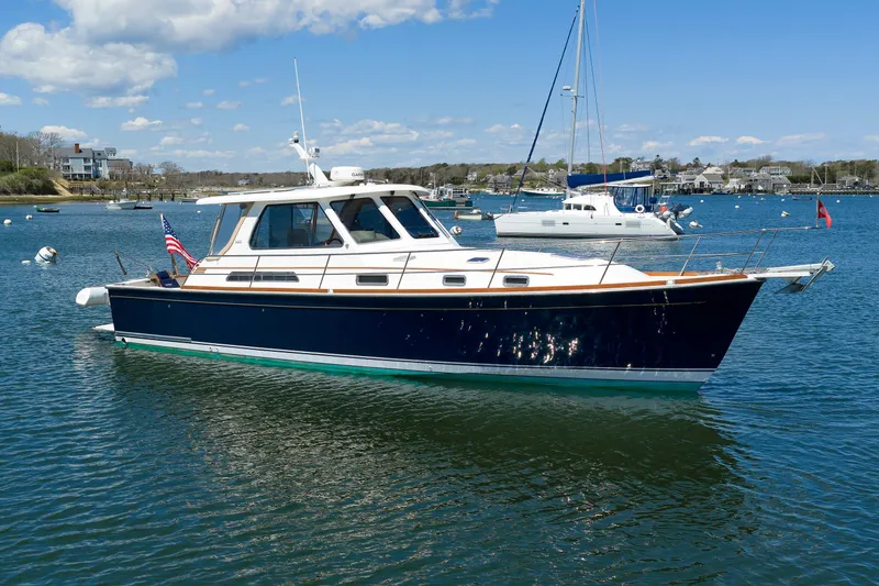 Slide: The Image of 2004 Sabre 42 Express yacht on calm water, with clear blue sky and distant sailboats. - 2