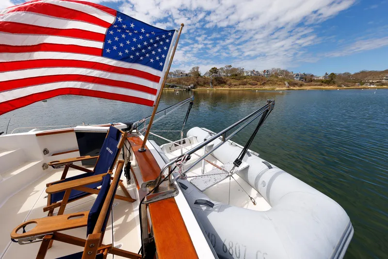 Slide: The Image of 2004 Sabre 42 Express yacht with American flag, docked by scenic shoreline. - 21