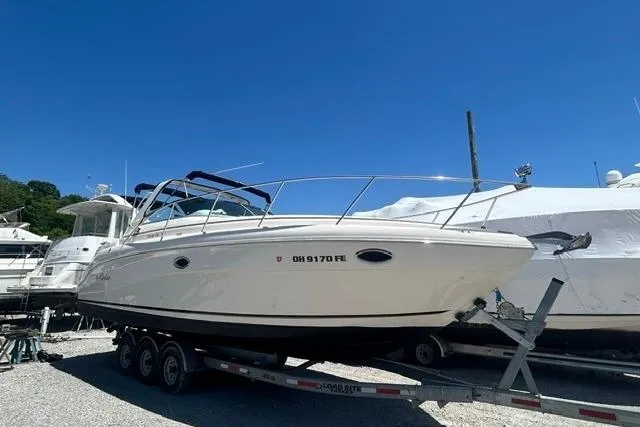 The Image of 2001 Rinker 310 Express Cruiser on trailer, parked outdoors under clear blue sky. - 1