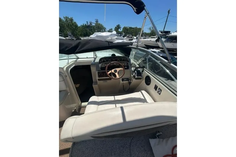 Slide: The Image of 2001 Rinker 310 Express Cruiser cockpit with steering wheel and controls, docked under clear sky. - 12