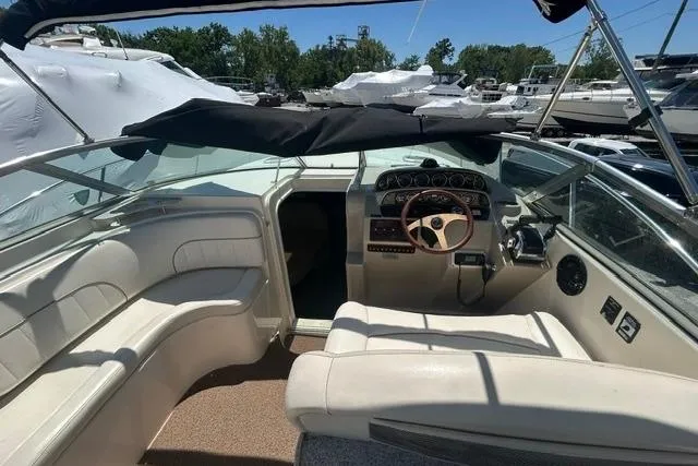 Slide: The Image of 2001 Rinker 310 Express Cruiser cockpit with steering wheel and seating, docked at marina. - 13