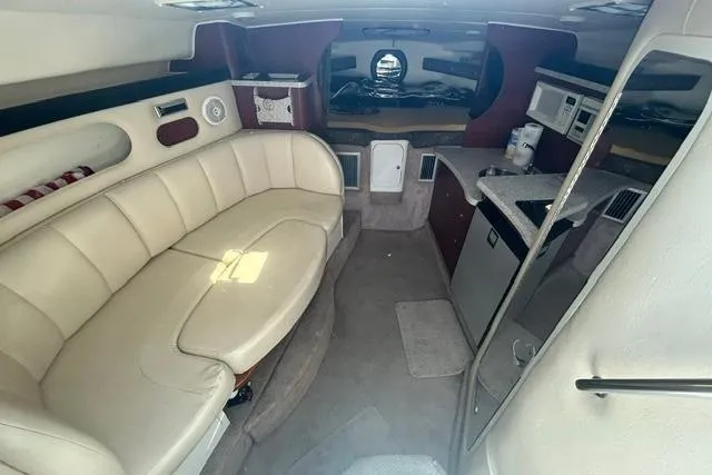 Slide: The Image of 2001 Rinker 310 Express Cruiser interior with beige seating and compact kitchenette. - 16