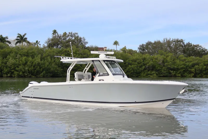 The Image of 2021 Pursuit S 328 Sport boat cruising on a calm waterway with lush greenery. - 0