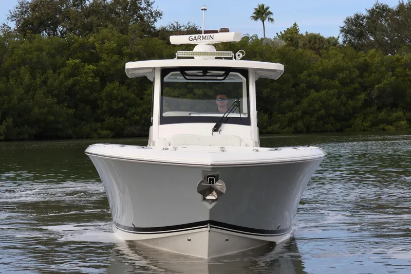 Slide: The Image of 2021 Pursuit S 328 Sport boat on calm water, surrounded by lush greenery. - 3