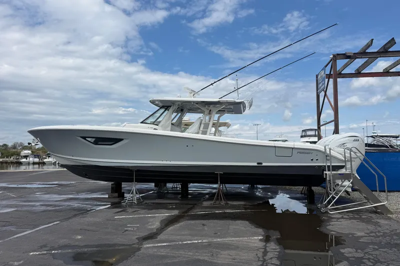 The Image of 2023 Pursuit S 428 Sport boat on dry dock under cloudy sky. - 1