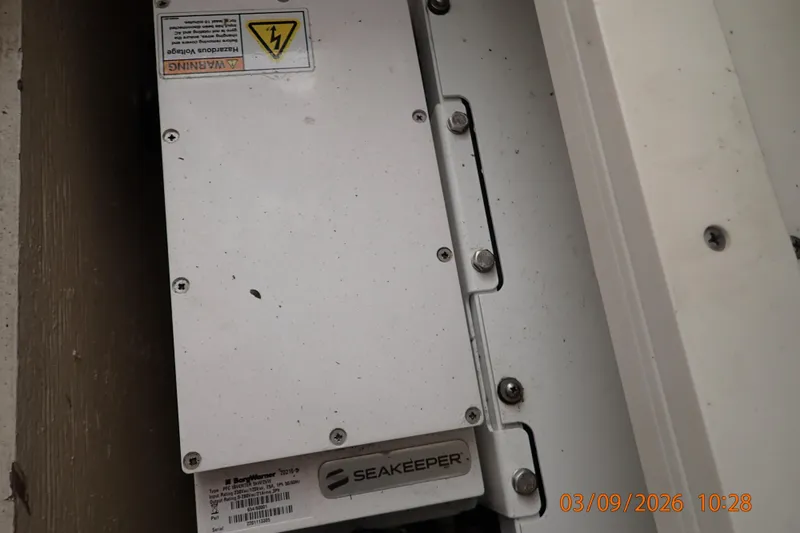 Slide: The Image of Seakeeper system in a 2023 Pursuit S 428 Sport boat, showing warning label and bolts. - 24