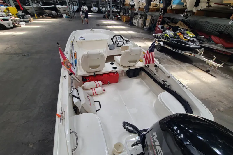 Slide: The Image of 2013 Boston Whaler 170 Super Sport boat in storage, featuring flags and safety equipment. - 12