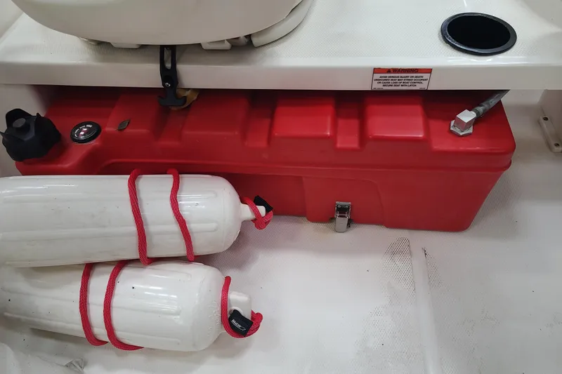 Slide: The Image of 2013 Boston Whaler 170 Super Sport boat interior with red fuel tank and white fenders. - 13