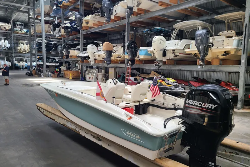 Slide: The Image of 2013 Boston Whaler 170 Super Sport in storage, featuring a Mercury outboard engine. - 5