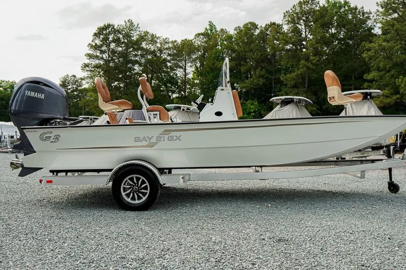 Slide: The Image of 2026 G3 Bay 21 GX Tunnel boat on trailer, featuring Yamaha engine, parked outdoors. - 2