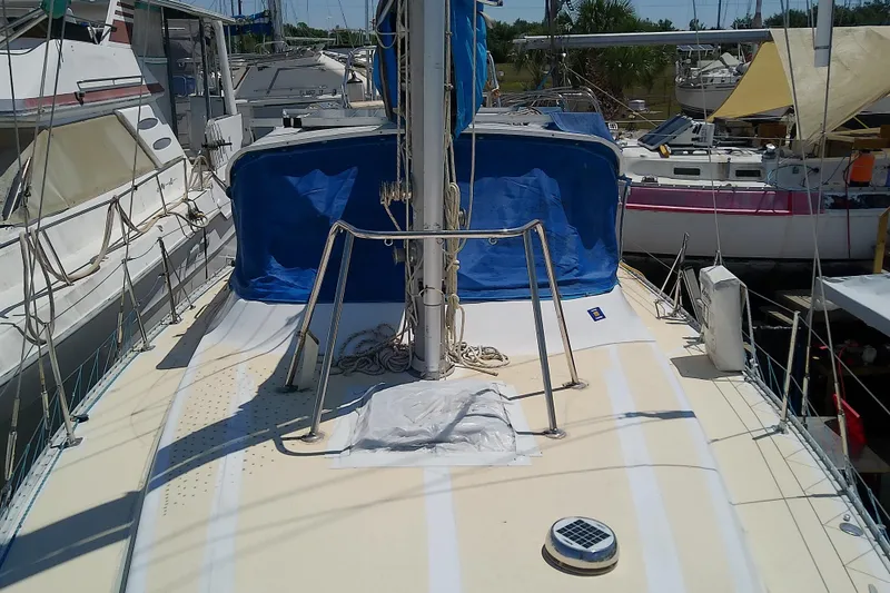 Slide: The Image of 1972 Morgan Out Island 41 sailboat deck with blue cover, docked among other boats. - 12