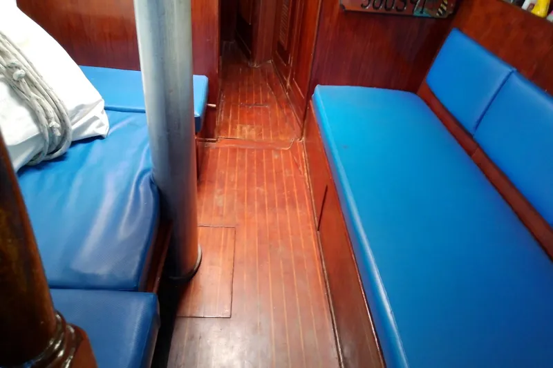 Slide: The Image of Interior of 1972 Morgan Out Island 41 sailboat with blue cushioned seating and wooden flooring. - 25