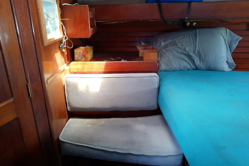 Slide: The Image of Interior of 1972 Morgan Out Island 41 sailboat with wooden paneling and blue bedding. - 42