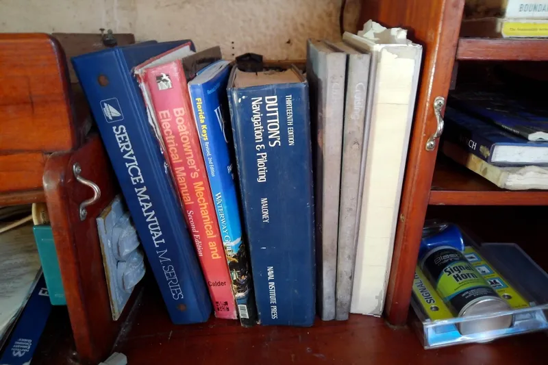 Slide: The Image of Books and manuals on a wooden shelf inside a 1972 Morgan Out Island 41 sailboat. - 46