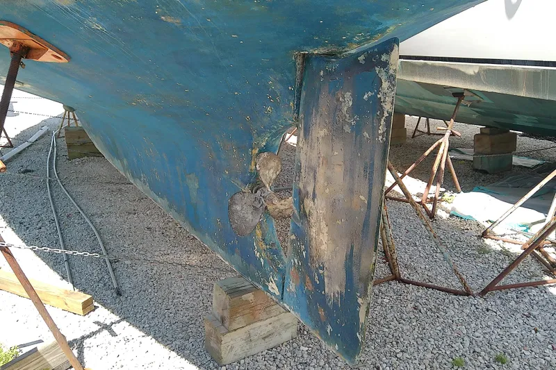 Slide: The Image of 1972 Morgan Out Island 41 sailboat hull and propeller on dry dock, showing wear and aging. - 5
