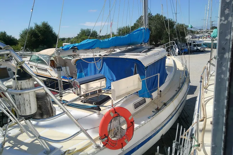 Slide: The Image of 1972 Morgan Out Island 41 sailboat docked, featuring blue covers and a red lifebuoy. - 14