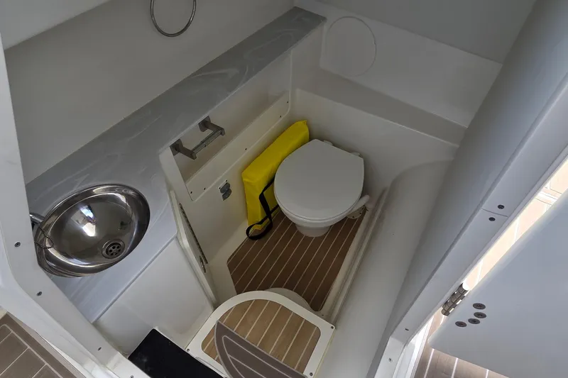 Slide: The Image of 2023 World Cat 280 DC-X boat bathroom with sink, toilet, and wooden flooring. - 19