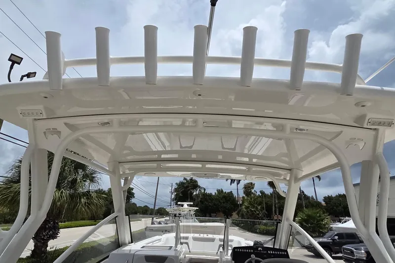 Slide: The Image of 2023 World Cat 280 DC-X boat with rod holders and canopy, parked outdoors. - 33