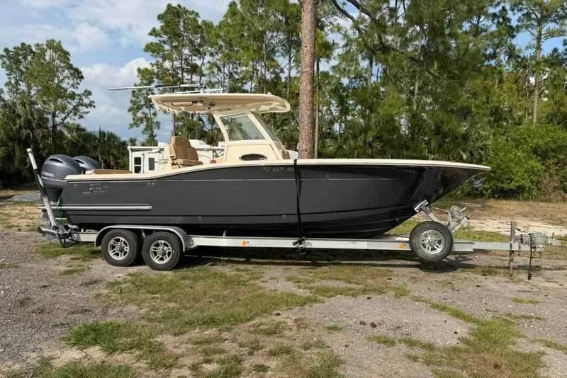 The Image of 2019 Scout 275 LXF boat on trailer, parked outdoors with trees in background. - 0