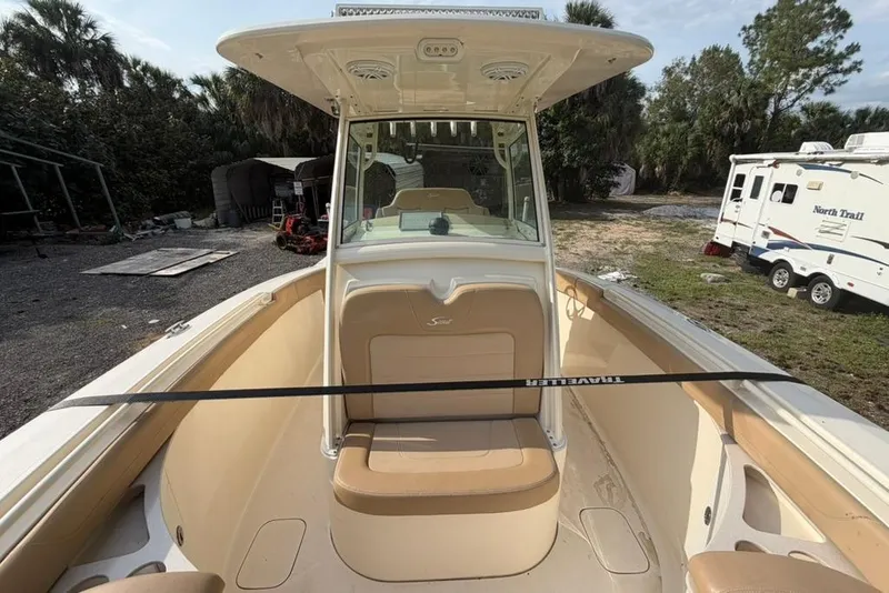 Slide: The Image of 2019 Scout 275 LXF boat with tan seating, parked outdoors near RV. - 12