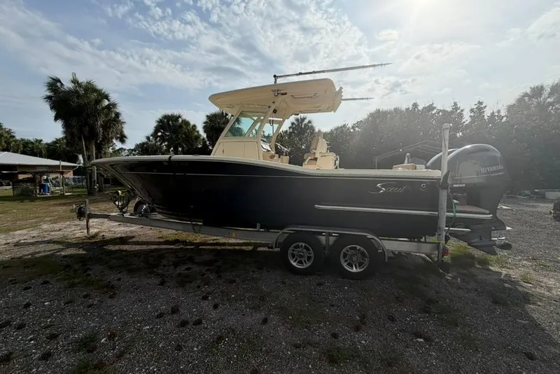 Slide: The Image of 2019 Scout 275 LXF boat on trailer, parked outdoors under a sunny sky. - 3