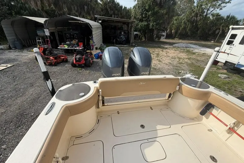 Slide: The Image of 2019 Scout 275 LXF boat with dual engines, parked near storage sheds and equipment. - 6