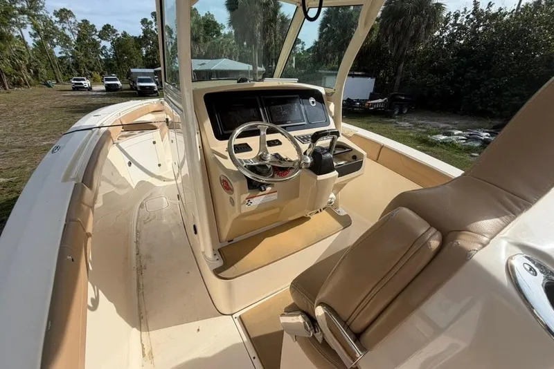 Slide: The Image of 2019 Scout 275 LXF boat interior with steering wheel and seating, parked outdoors. - 8