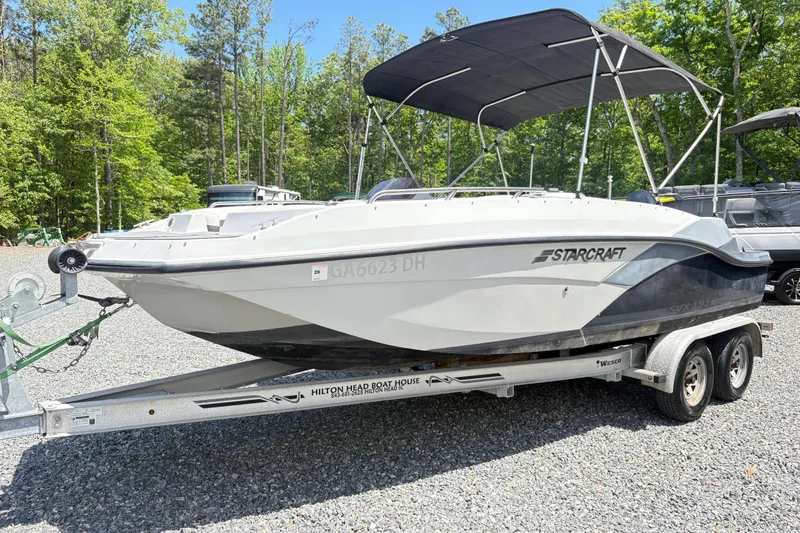 Slide: The Image of 2022 Starcraft SVX 191 OB boat on trailer, parked outdoors with trees in background. - 5