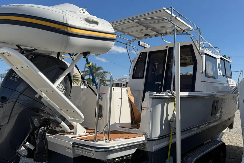 Slide: The Image of 2024 Ranger Tugs R-27 boat with Yamaha engine and inflatable dinghy, docked under clear sky. - 1