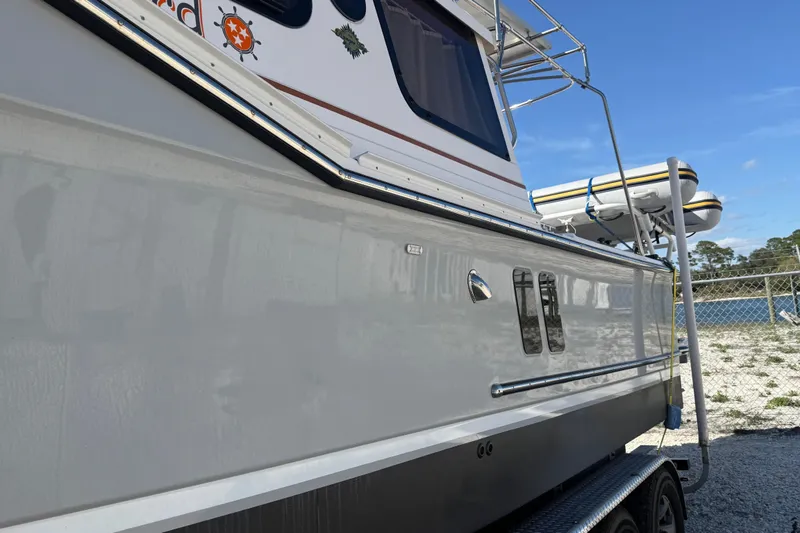 Slide: The Image of 2024 Ranger Tugs R-27 boat side view with trailer, docked outdoors. - 2