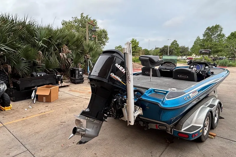 Slide: The Image of 2009 Triton 22 TrX boat with Mercury outboard motor, parked outdoors near palm trees. - 8