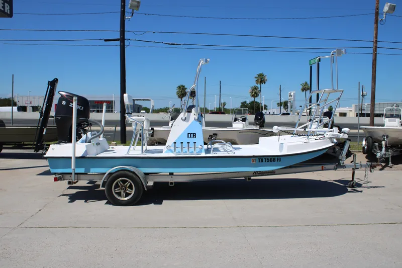 Slide: The Image of 2017 CCB Phoenix boat with Suzuki motor on trailer, parked outdoors. - 2