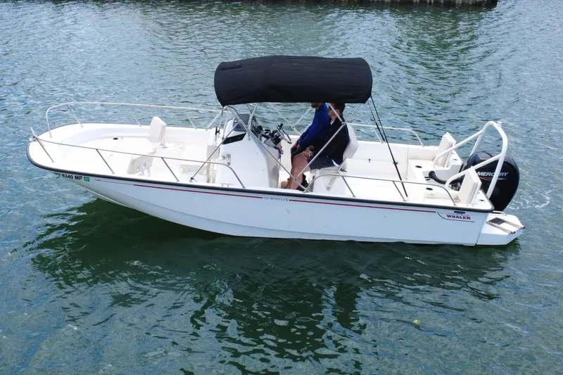 Slide: The Image of 2020 Boston Whaler 210 Montauk boat on water, featuring a black canopy and Mercury engine. - 1