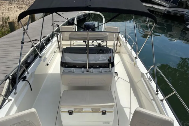 Slide: The Image of 2020 Boston Whaler 210 Montauk boat with canopy, docked by the water. - 19
