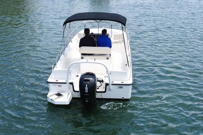 Slide: The Image of 2020 Boston Whaler 210 Montauk boat on water, rear view with two passengers. - 7